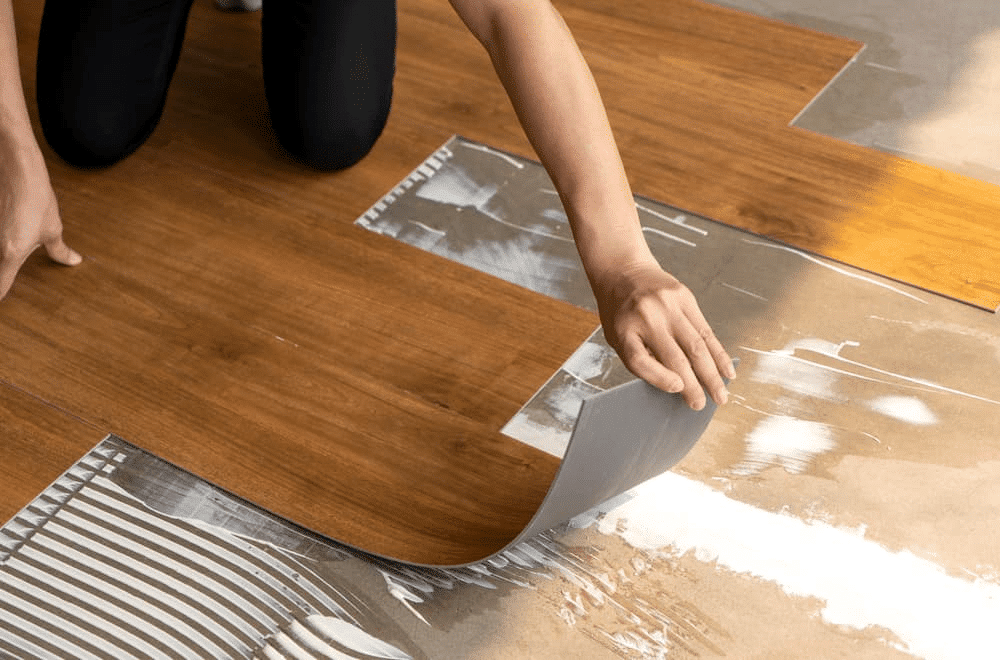 Person installing vinyl flooring by peeling back the sheet